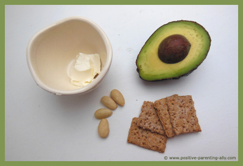 Ingredients for avocado spread on whole grain crackers.