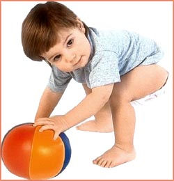 Toddler reaching down for soft ball.