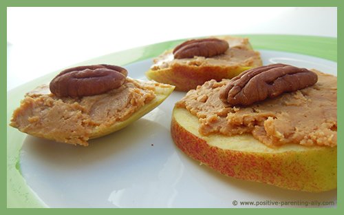 Healthy recipes for kids with apple slices, peanut butter and pecan nuts.